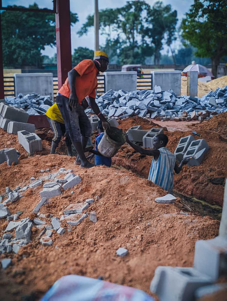 Local workers at a construction site handling bricks and materials in Kaduna, Nigeria.