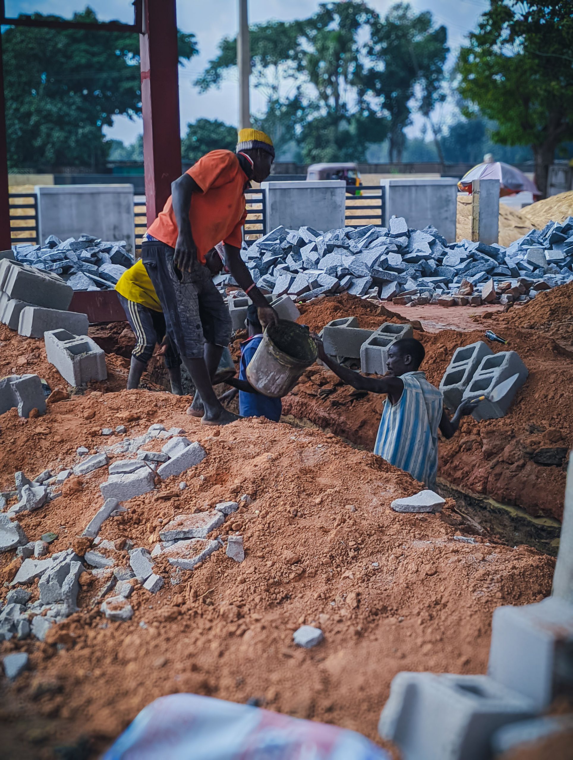 Local workers at a construction site handling bricks and materials in Kaduna, Nigeria.